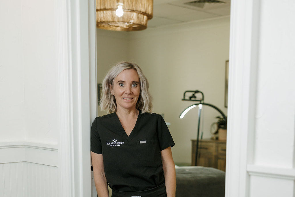 Woman in a black scrub top standing in a medical or clinical setting.